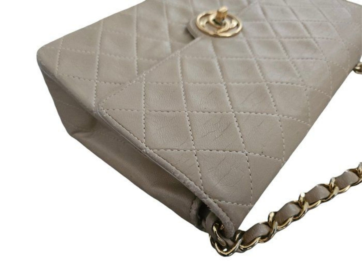 Chanel beige quilted leather flap bag with gold hardware and interlocking CC turn-lock closure.