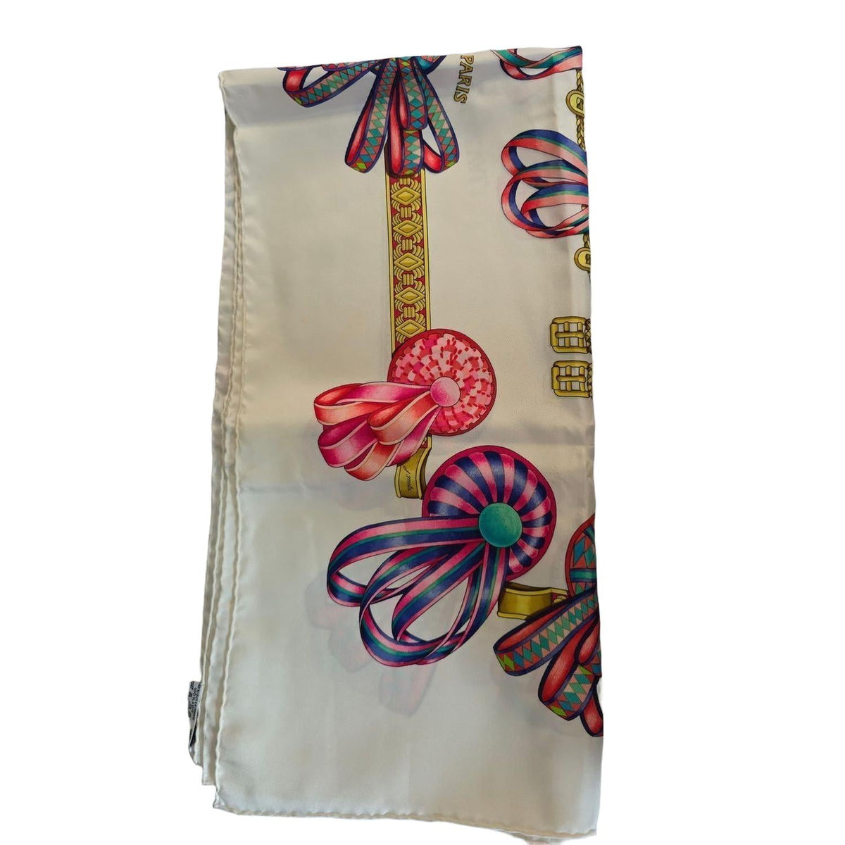 Hermès beige silk scarf featuring equestrian ribbon pattern and hand-rolled edges.