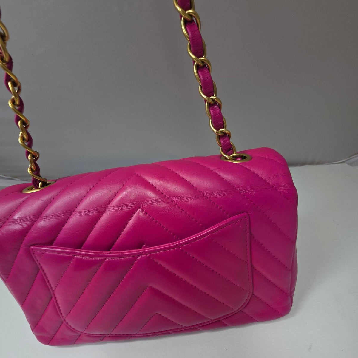 Chanel pink mini messenger bag in chevron leather with gold CC clasp and hardware.