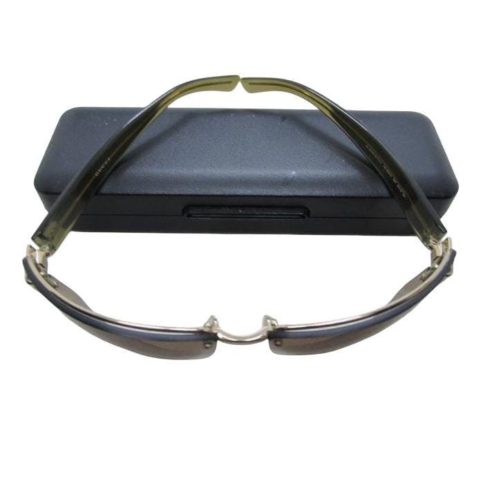 Gucci half-rim wrap sunglasses in green and gold, featuring vintage design and logo.