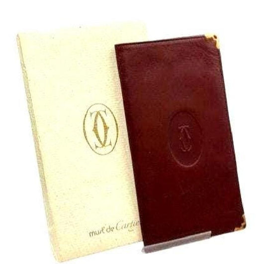 Cartier bifold wallet burgundy Bordeaux leather with gold-plated corners and 'Cartier Paris' logo.