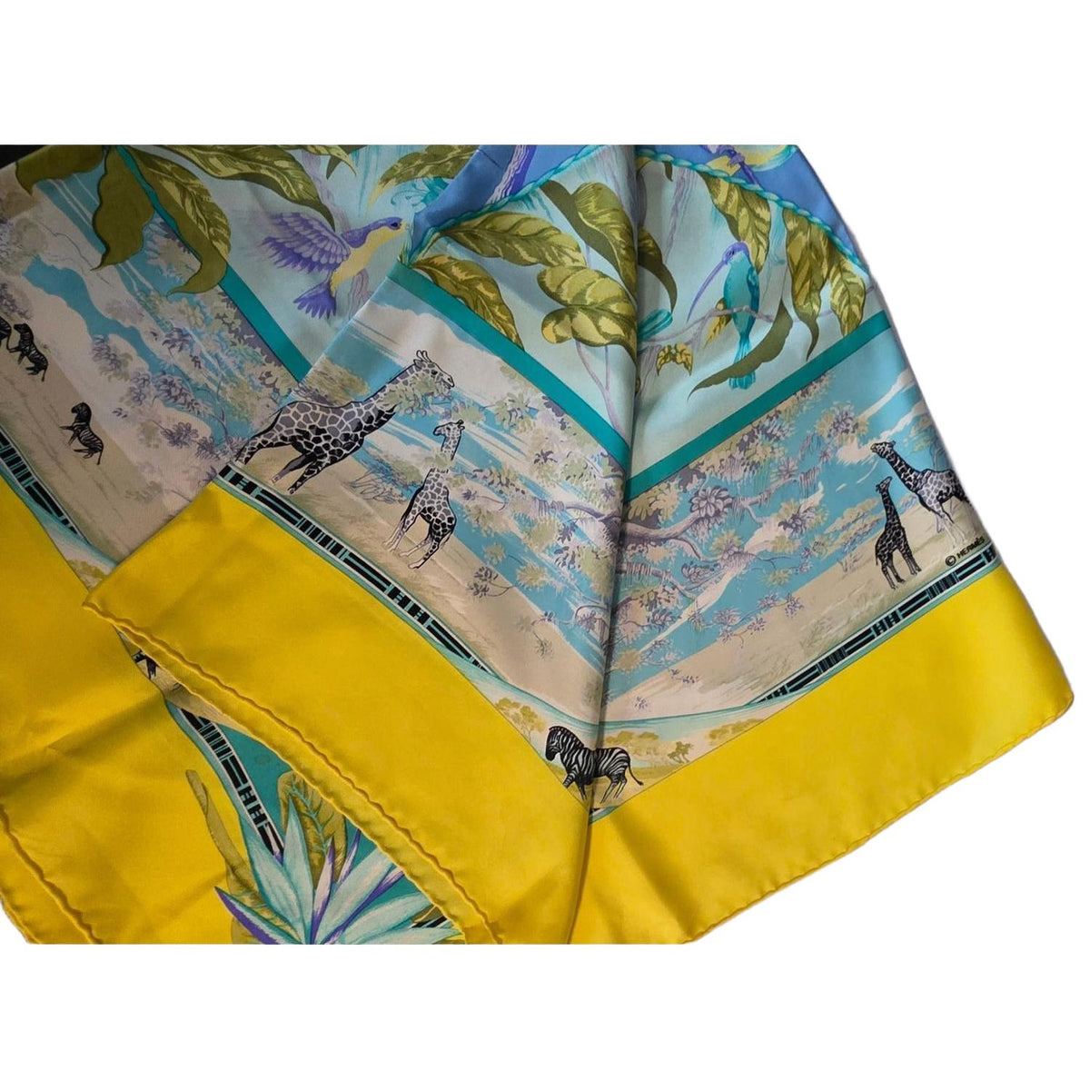 Hermès yellow silk twill shawl featuring tropical animal prints and hand-rolled edges.