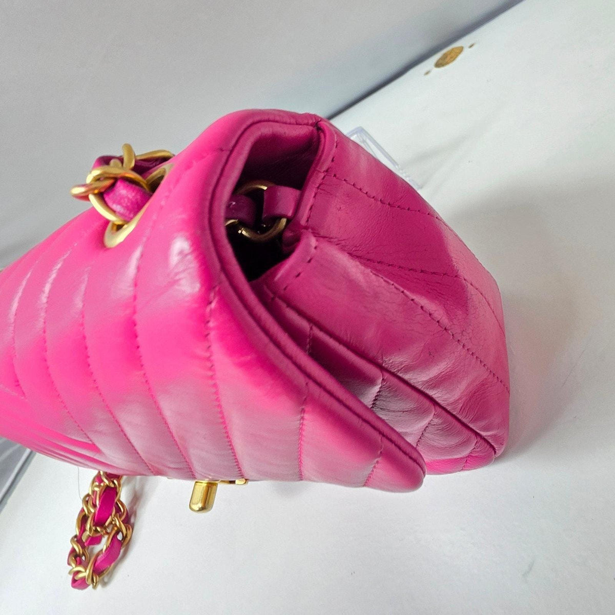 Chanel pink mini messenger bag in chevron leather with gold CC clasp and hardware.