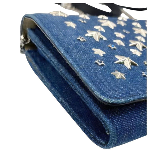 Jimmy Choo blue denim crossbody bag with silver star studs and chain-link strap.