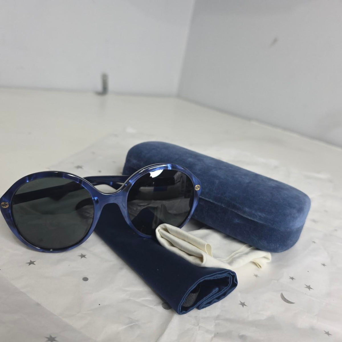 Gucci blue sunglasses with black lenses, featuring logo and giftable condition.