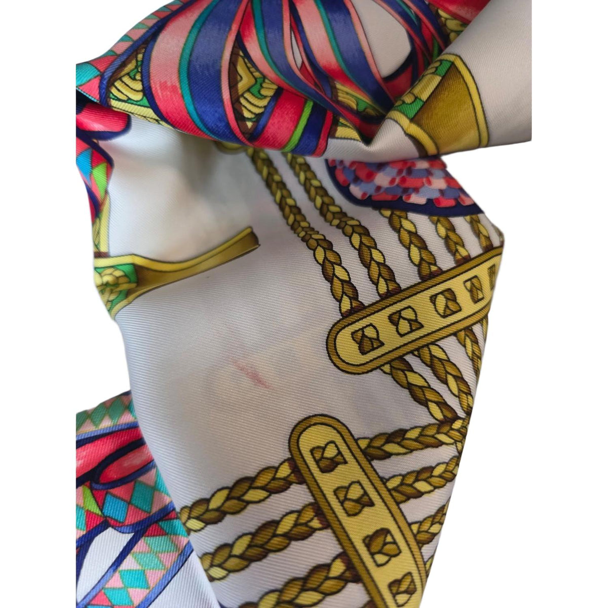 Hermès beige silk scarf featuring equestrian ribbon pattern and hand-rolled edges.