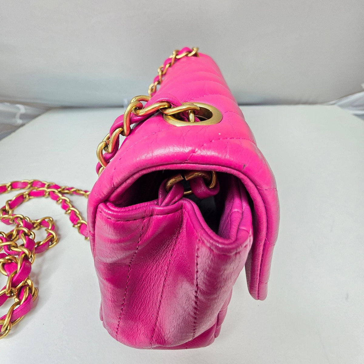 Chanel pink mini messenger bag in chevron leather with gold CC clasp and hardware.