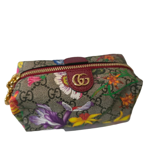 Gucci cream cosmetic case with floral pattern, GG Supreme canvas, and gold hardware.