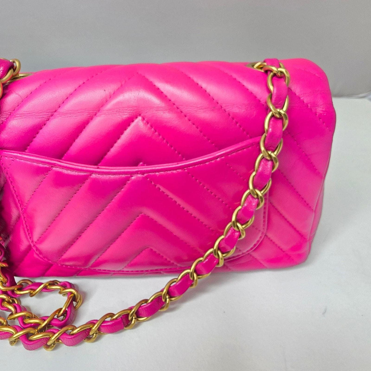 Chanel pink mini messenger bag in chevron leather with gold CC clasp and hardware.