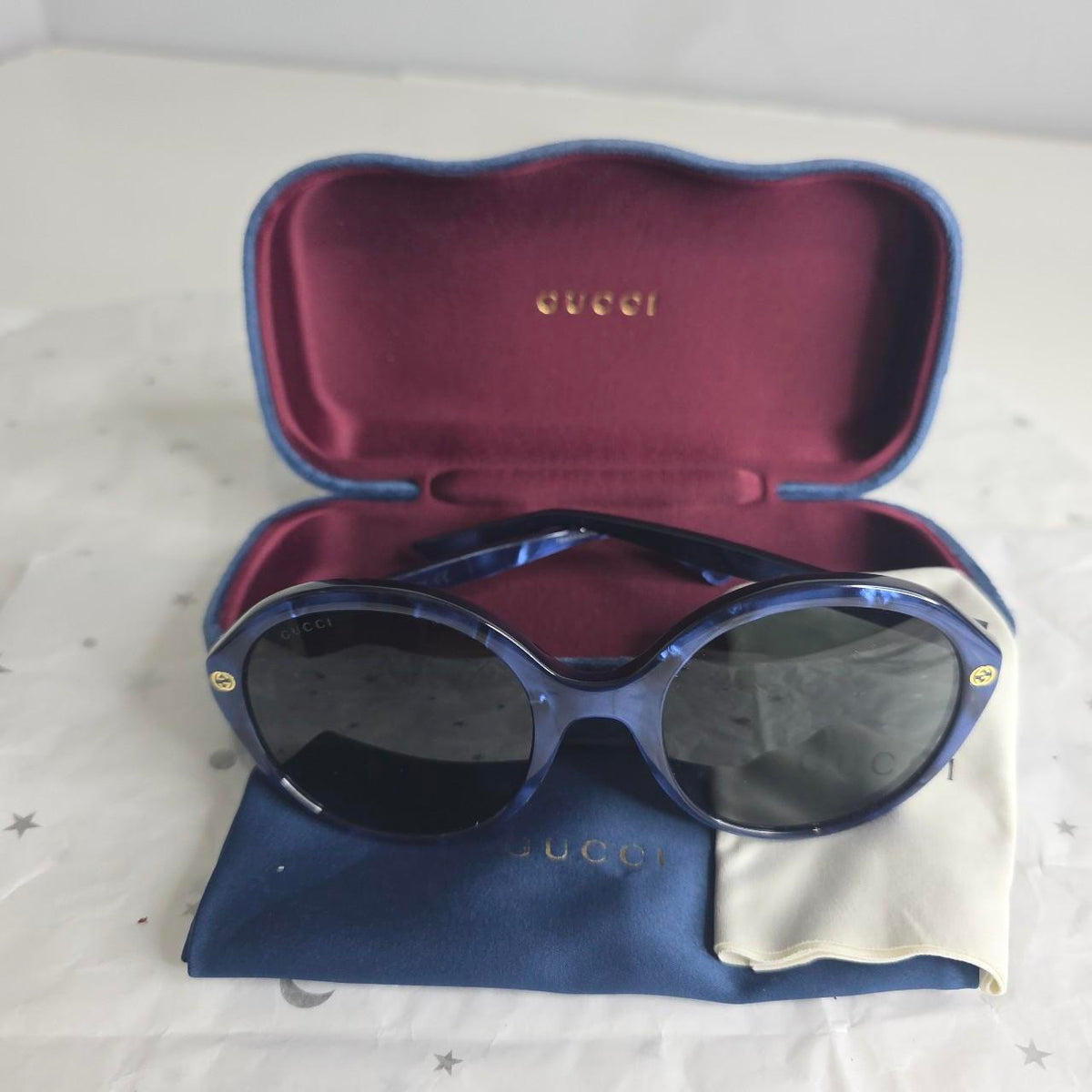 Gucci blue sunglasses with black lenses, featuring logo and giftable condition.
