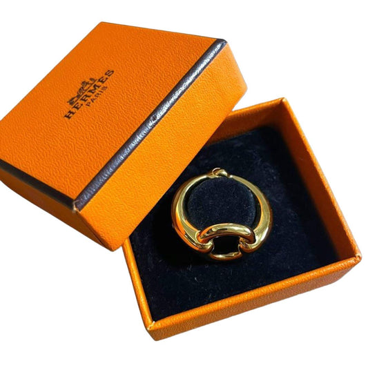 Hermès gold plated mors scarf ring engraved logo with orange accents and equestrian design.
