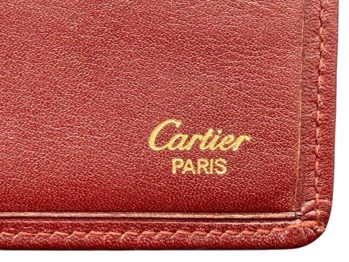 Cartier bifold wallet burgundy Bordeaux leather with gold-plated corners and 'Cartier Paris' logo.