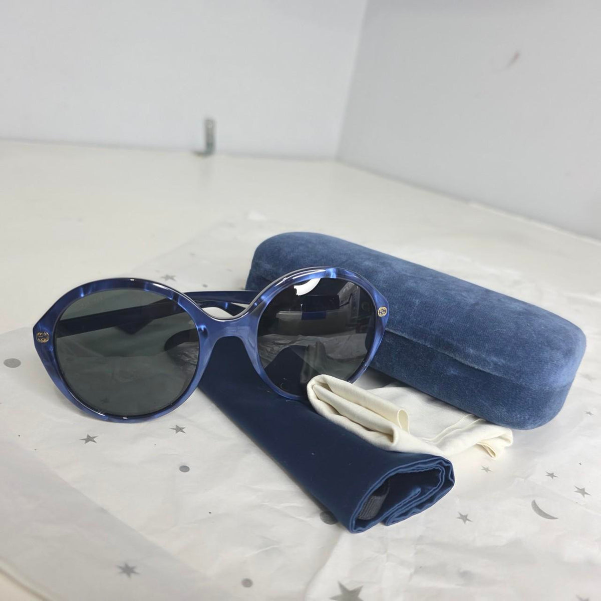 Gucci blue sunglasses with black lenses, featuring logo and giftable condition.