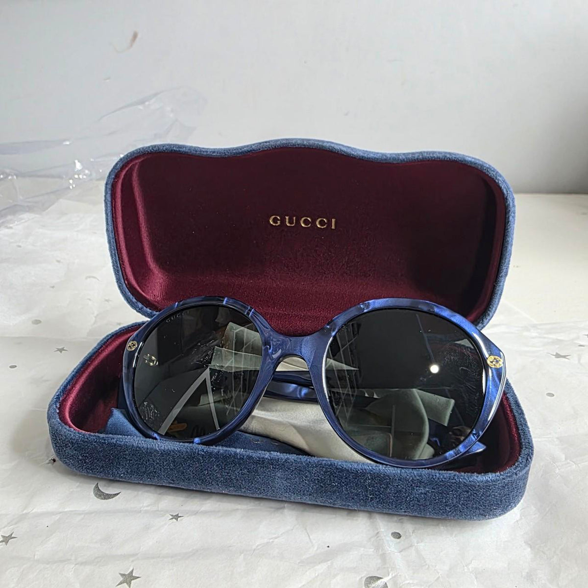 Gucci blue sunglasses with black lenses, featuring logo and giftable condition.