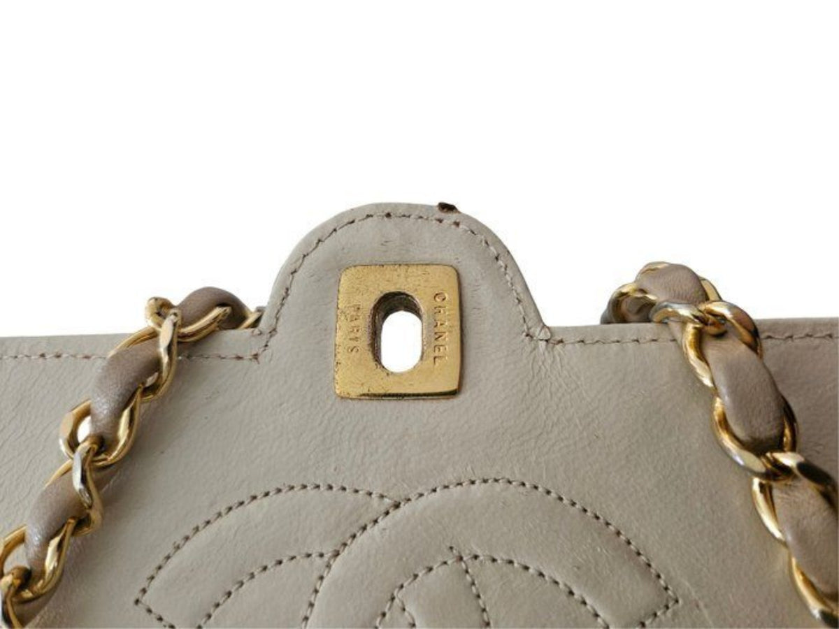 Chanel beige quilted leather flap bag with gold hardware and interlocking CC turn-lock closure.