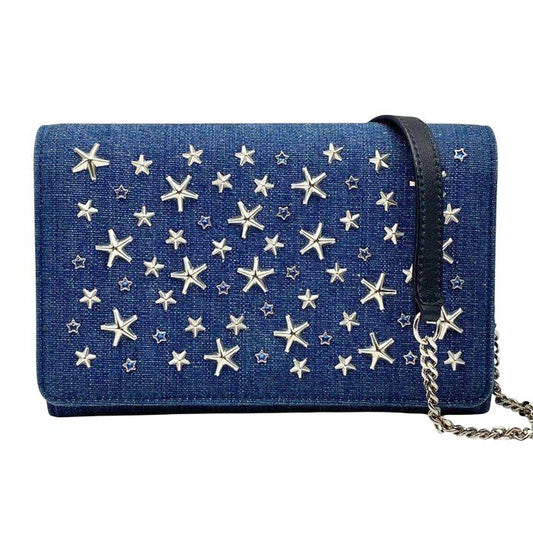 Jimmy Choo blue denim crossbody bag with silver star studs and chain-link strap.