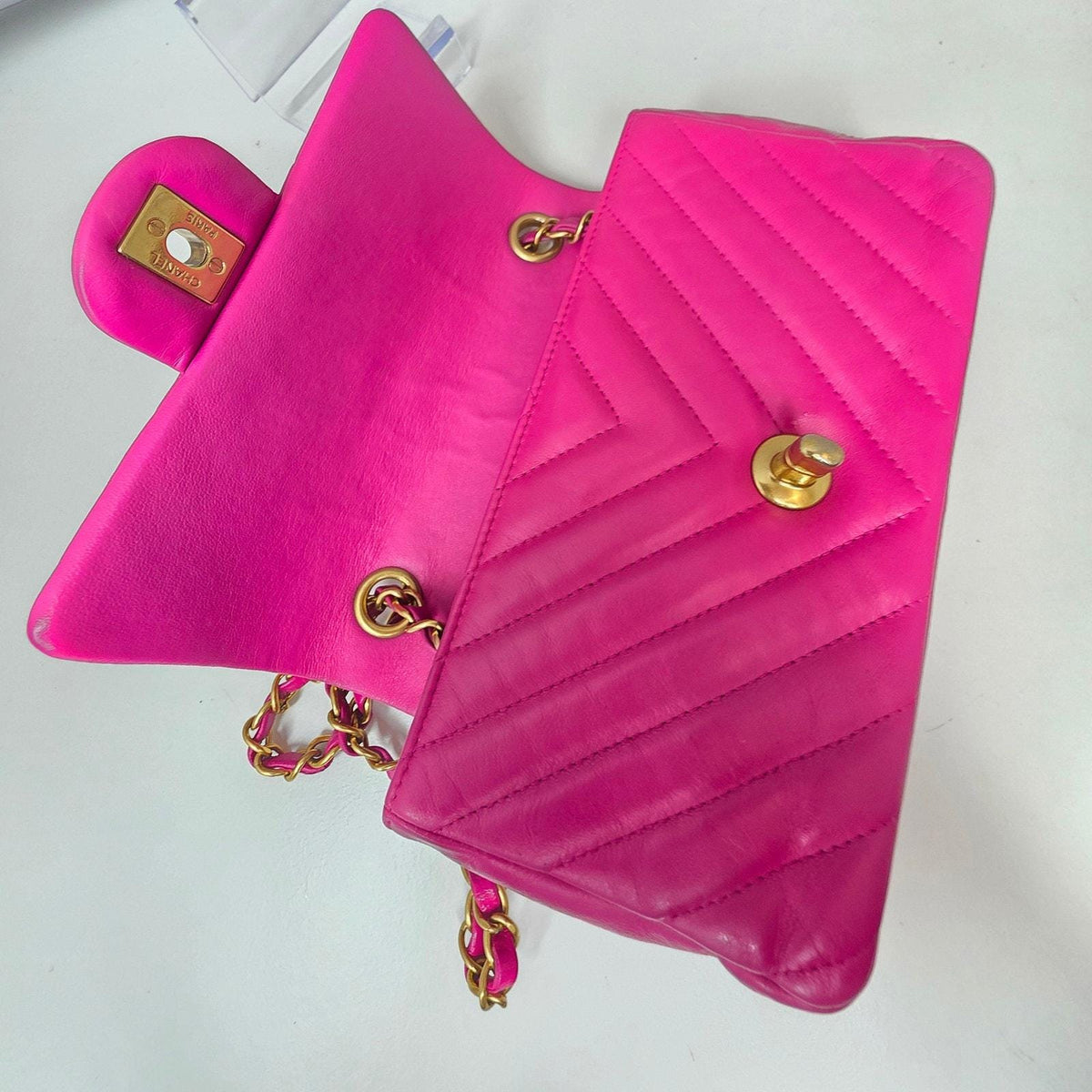 Chanel pink mini messenger bag in chevron leather with gold CC clasp and hardware.