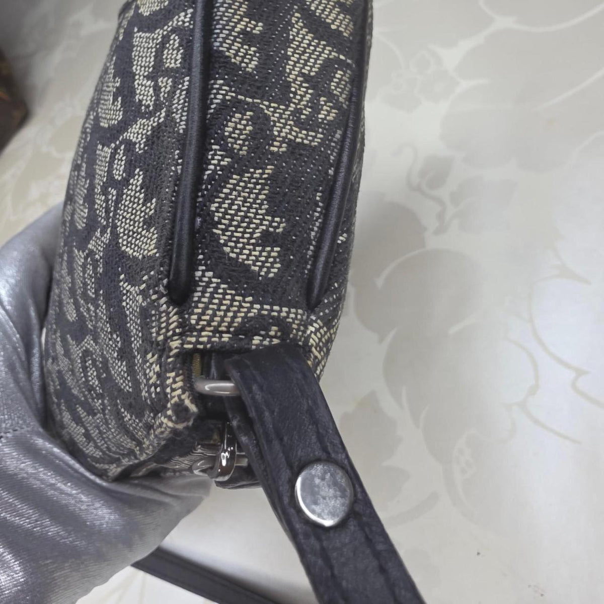 Dior messenger bag in grey, blue, and black with silver accents and saddle shape.