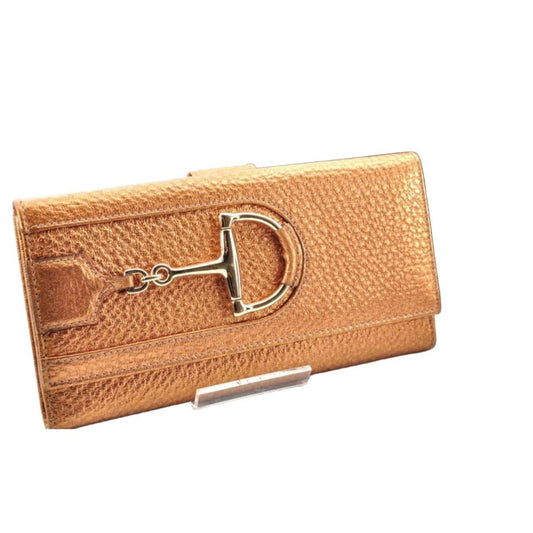 Gucci gold leather wallet with iconic horsebit detail and metallic finish.