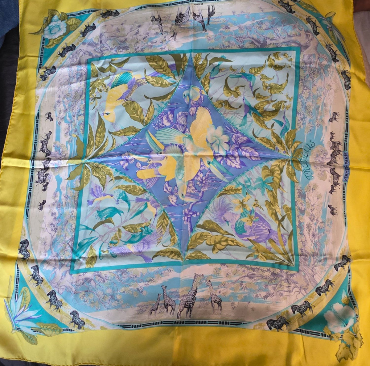 Hermès yellow silk twill shawl featuring tropical animal prints and hand-rolled edges.