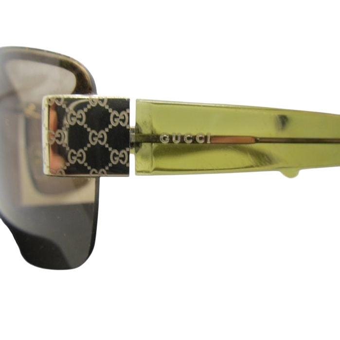 Gucci half-rim wrap sunglasses in green and gold, featuring vintage design and logo.