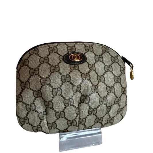 Gucci gold cosmetic pouch with iconic GG monogram canvas and leather trim.