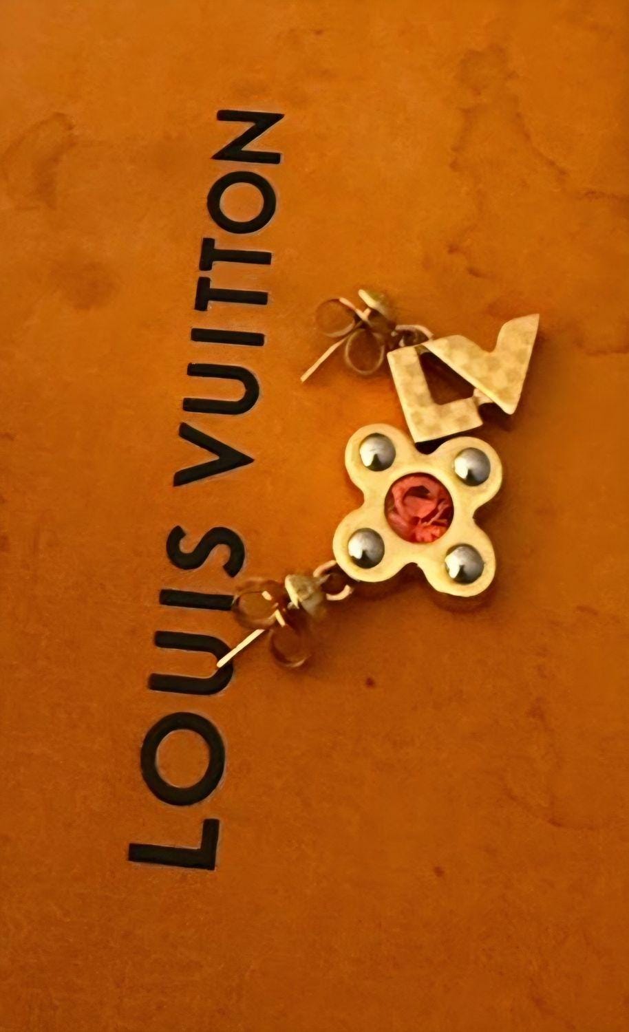 Louis Vuitton gold earrings with red stone and iconic monogram flower motif.