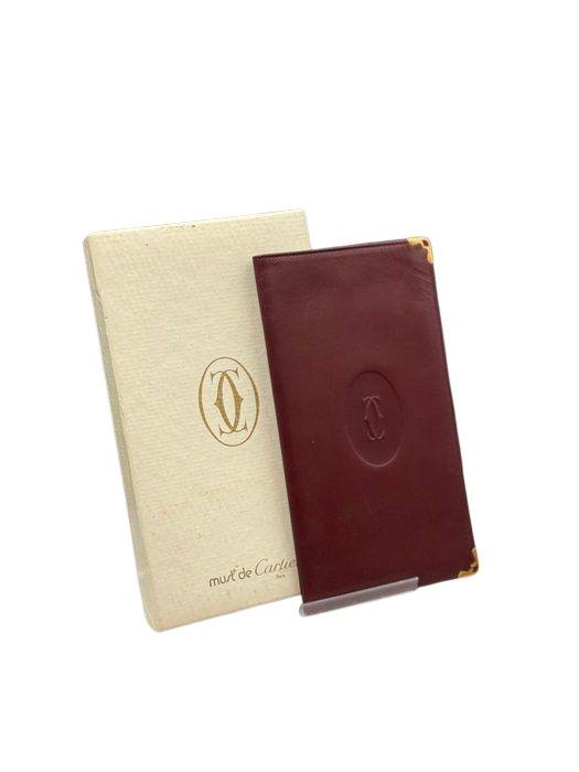 Cartier bifold wallet burgundy Bordeaux leather with gold-plated corners and 'Cartier Paris' logo.
