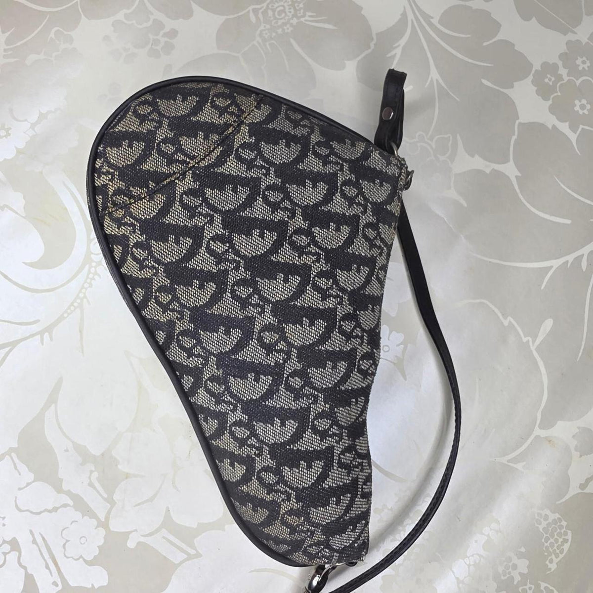 Dior messenger bag in grey, blue, and black with silver accents and saddle shape.