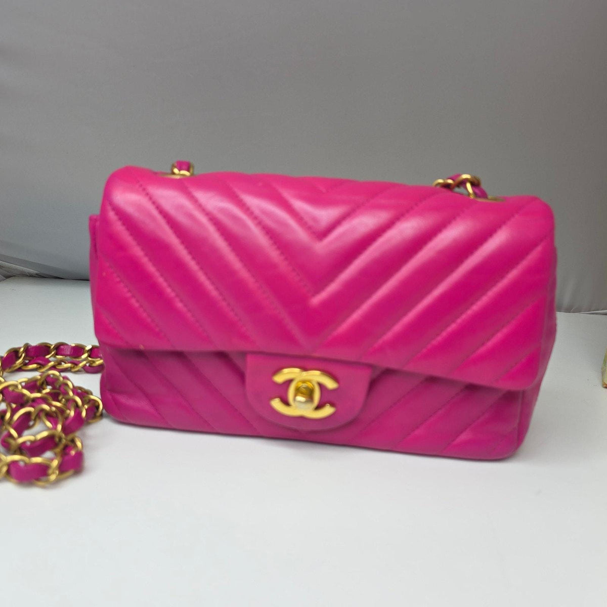 Chanel pink mini messenger bag in chevron leather with gold CC clasp and hardware.