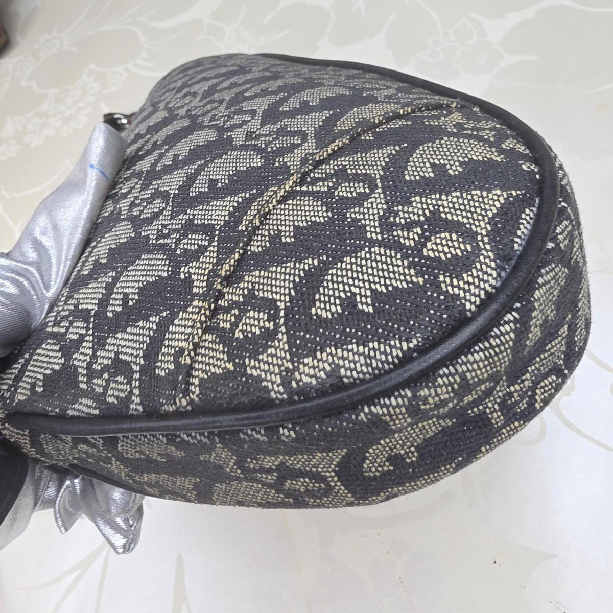 Dior messenger bag in grey, blue, and black with silver accents and saddle shape.